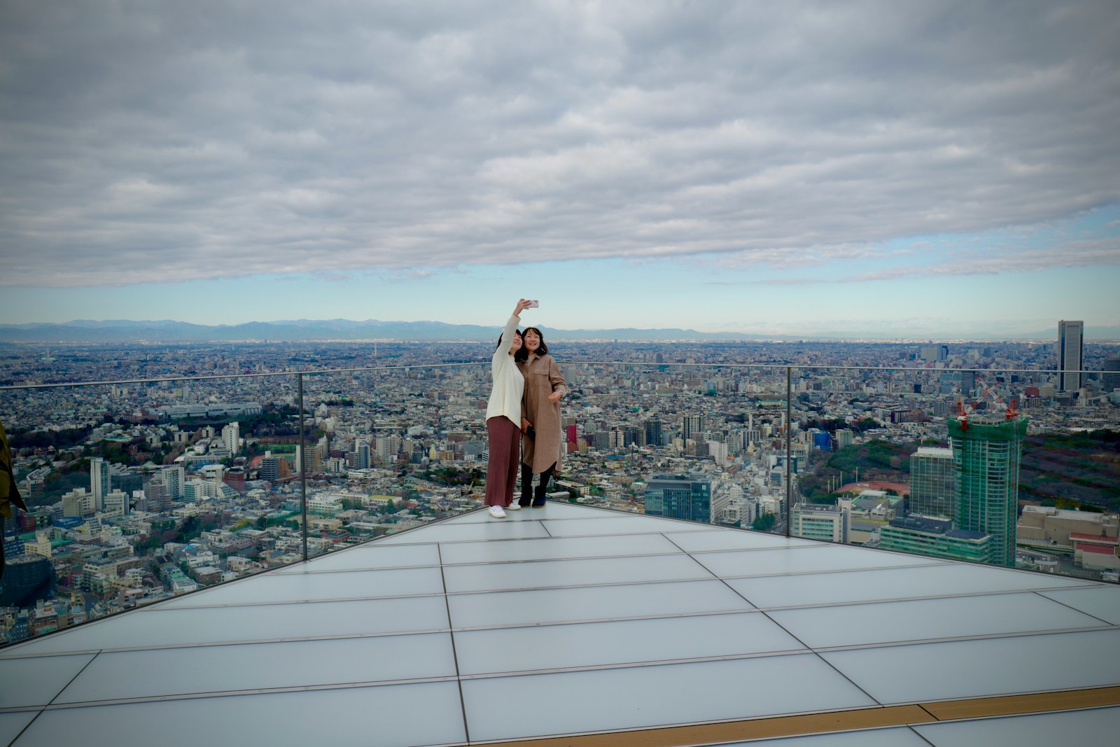woman in brown coat standing on top of building during daytime