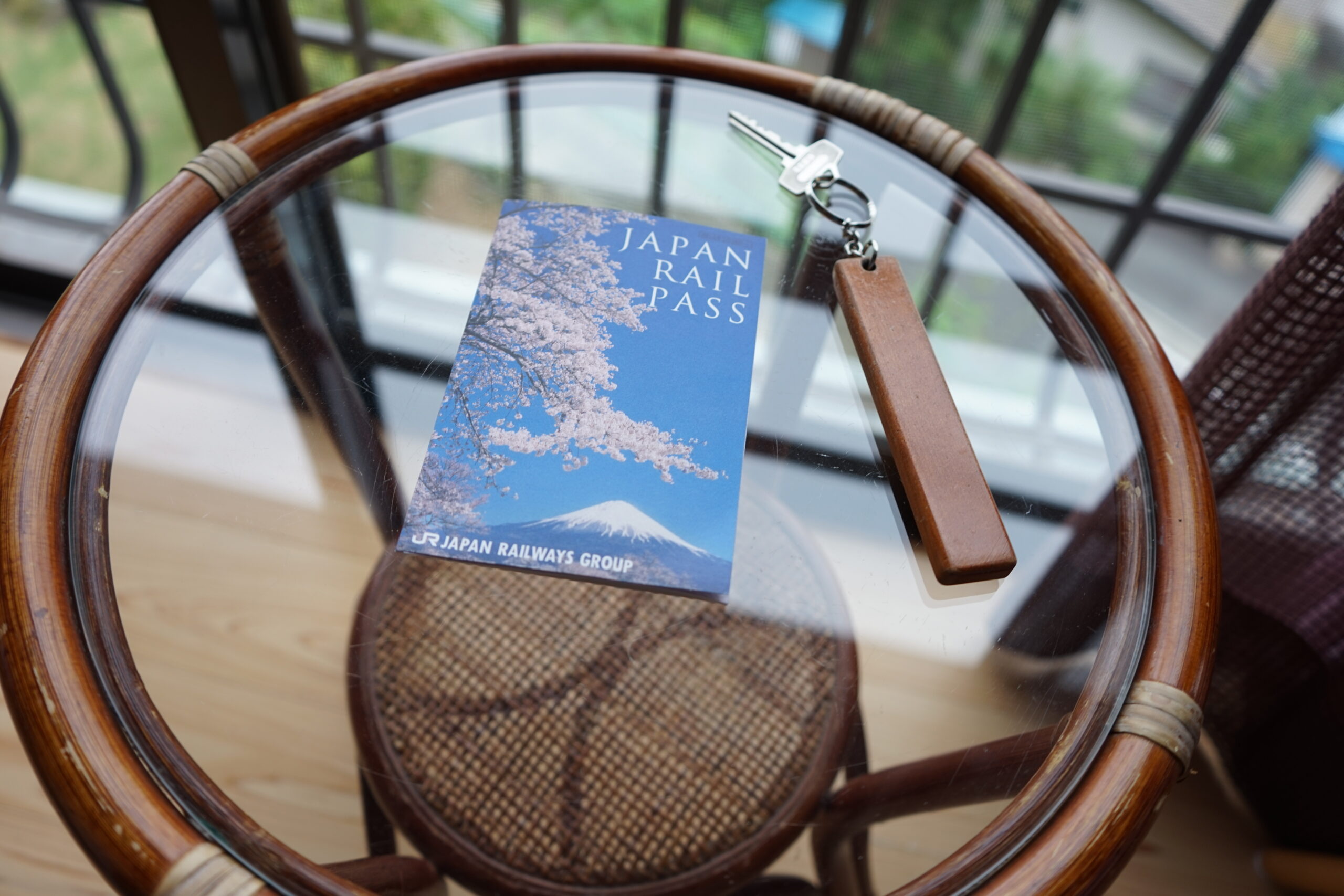 Japan Rail Pass booklet and ticket held up in front of a Shinkansen at the platform